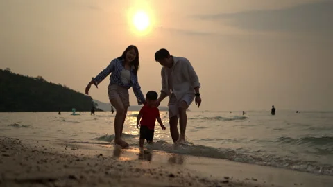 Parents with their young child while walking in shallow sea water Stock Footage 338388656