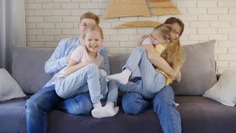 Parents tickling daughters on sofa Vidéo 107404335