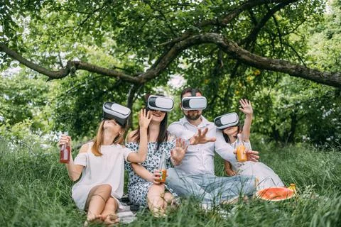 Parents with two kids using VR headset at outdoors picnic Stock Photos