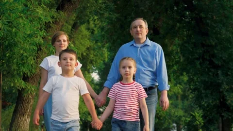 Parents walk hand in hand behind son and smiling daughter also joining hands Stock Footage 258965057