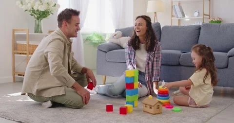 Parents watch daughter stack colorful blocks during playful family time at home 動画素材 319458059