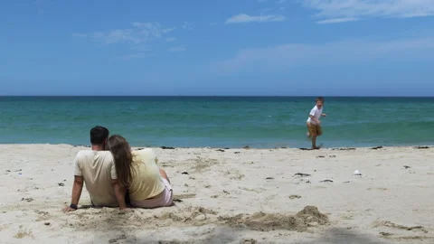 The parents watch their son playing on the shore. Stock Footage 310935836