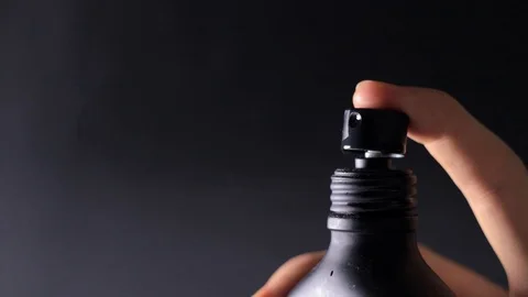 Parfume gets sprayed out of a black bottle / 40% Slow-motion Stock Footage 122041700