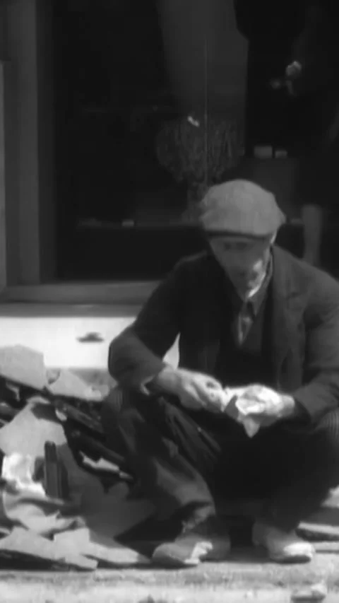 PARIS - 1930s - Two workmen eat lunch on the curb of a street in Paris, France. 스톡 동영상 342250132