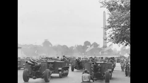PARIS - 1944: Artillery column - Half-tracks tow guns past a flag-lined obelisk Stockbeeldmateriaal 344005849