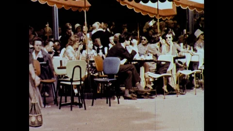 PARIS 1960s: crowd sits, talks, eats at outdoor area of café, pedestrians walk Stock Footage 126013487