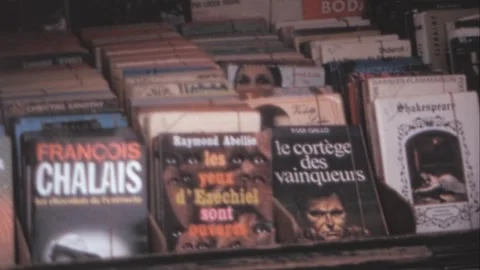 Paris - 1975: Camera pans over bookshelves filled with books in a flea market Stock Footage 282709327