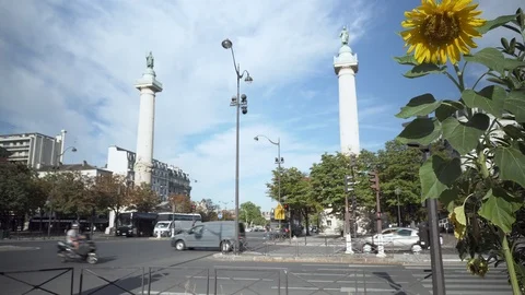 In Paris, the 2 Colonnes du Trone with road trafic and a sunflower in the Vidéo 94484322
