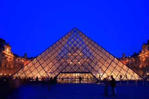 Paris - april 16: entrance of louvre pyramid shines at dusk during the summer Stock Photos