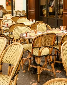 Paris cafe terrace with empty wicker chairs and small tables, inviting rela.. Stock Photos