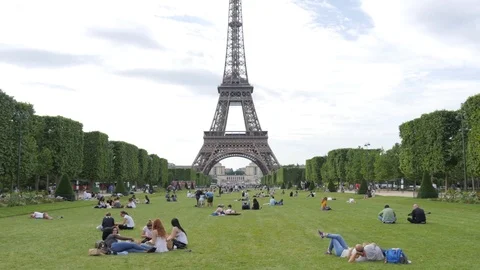 Paris Champ de Mars green lawn with people lie and rest admiring the Eiffel Tour Stock Footage 76860391