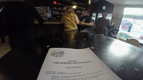 Paris Craft Beer Bar Menu in Foreground with Patrons Socializing at Counter Stock Footage 346289376