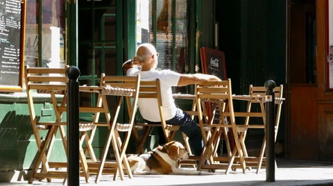 Paris, France. Bar owner and dog sitting in the bright sunshine. Stock Footage