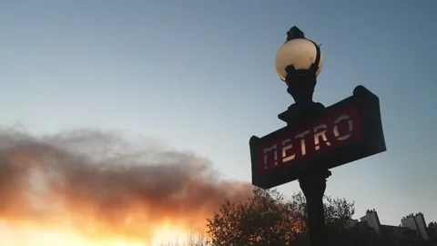 Paris Metro sign with a column of smoke in the sky during sunset Stock Footage 312872853
