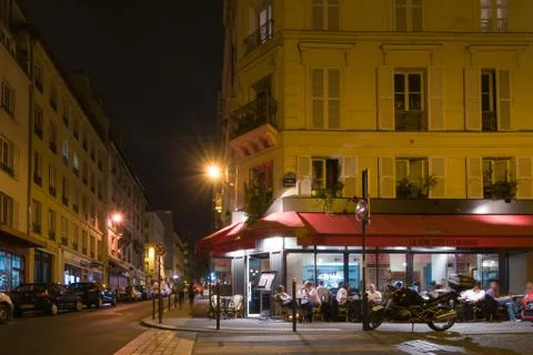 Paris by night. The people sit and talk in a cafe. Stock Photos