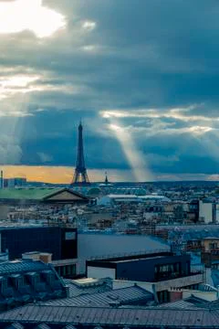 Paris skyline with rooftops and the Eiffel tower on a cloudy day with sun rays Foto stock