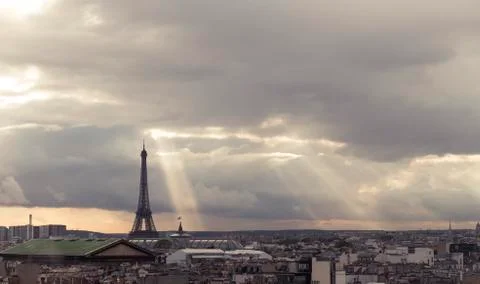 Paris skyline with rooftops and the Eiffel tower on a cloudy day with sun rays 스톡 사진