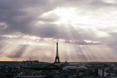 Paris skyline with rooftops and the Eiffel tower on a cloudy day with sun rays Foto stock