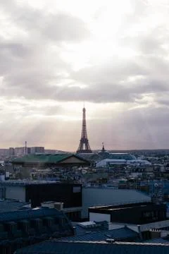Paris skyline with rooftops and the Eiffel tower on a cloudy day with sun rays 库存照片