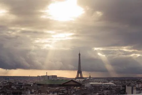 Paris skyline with rooftops and the Eiffel tower on a cloudy day with sun rays Stock Photos