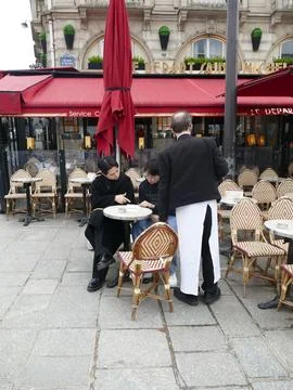 Parisian caf server writing down order for outdoor diners, capturing urban .. Stock-Fotos