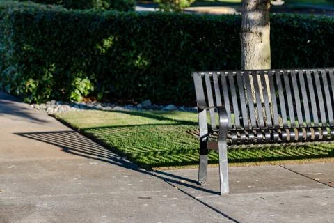 Park bench casting a shadow on a walkway Stock Photos