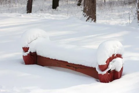 A park bench covered with a large layer of snow Stock Photos