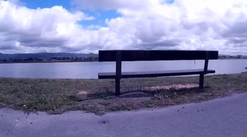 Park Bench Facing Bay Low Aerial Over Calm Water Under Clouds Stock Footage 37579829