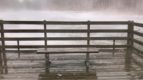 Park Bench Looking Out Onto Misty Pond During Winter Rainstorm Stock Footage 85195574