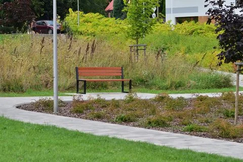 Park bench by a pedestrian path on a cloudy day. Rest. Day. Stock Photos