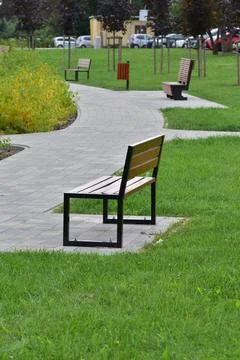 Park bench by a pedestrian path on a cloudy day. Rest. Day. Stock Photos