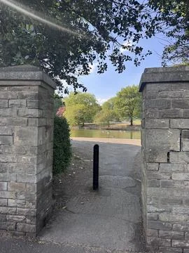 Park gate, beautiful green trees near pond and old entrance made out of bricks Stock Photos