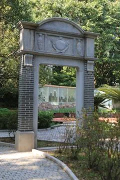 The park gate is made of gray bricks and concrete, with an arched top that .. Stock Photos