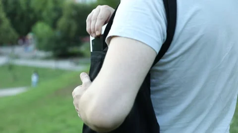 In the park, a guy takes a tablet out of his bag and clicks on the screen, lame Stock Footage 134913261