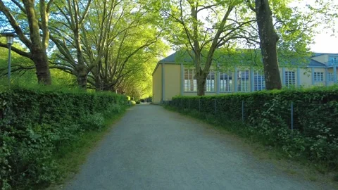 Park pathway with yellow building and large trees in Zurich Stock Footage 334082151