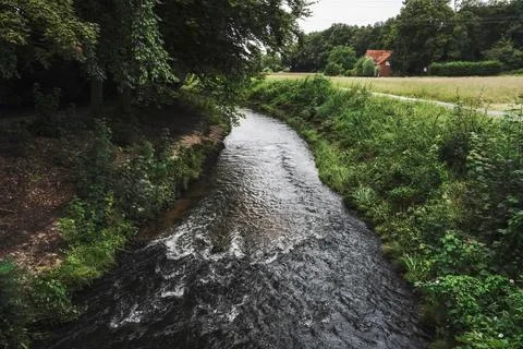 A park with a river gently winding through greenery and trees Stock Photos