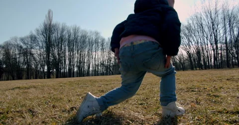 In the park a small child gets up from the ground and goes to the playground Stock Footage 151526382