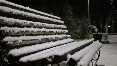 Park, snow sits on an empty bench. Night time. Vídeos de archivo 304662182