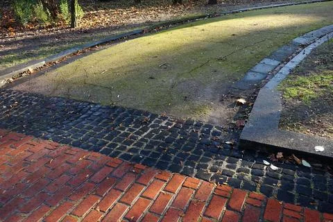 Park walking paths made of stones and old green asphalt in the fall Stock Photos