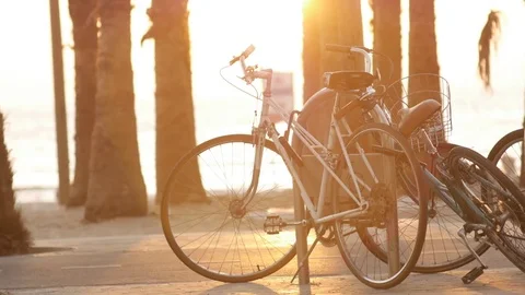 Parked bicycle on the beach. at sunset time. people passing by Stock Footage 75397383
