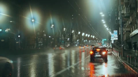 A parked car backs up against the background of wet asphalt with city lights Stock Footage 240620426
