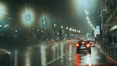 A parked car backs up against the background of wet asphalt with city lights Stock Footage 242626607