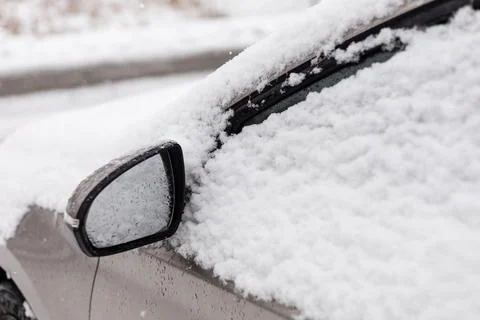 A parked car is covered with a thick layer of fresh snow. Large snowflakes .. Stock Photos