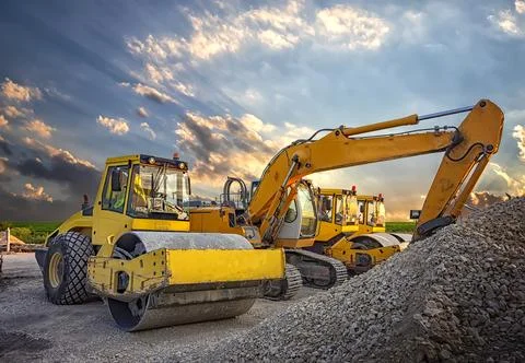 Parked drum roller and excavators at the construction site, after work Stock Photos