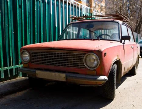 Parked old rusty red Soviet car. Stock Photos