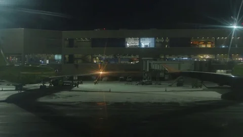 The parked plane to the terminal. The view from the window in the winter Stock Footage 78729139