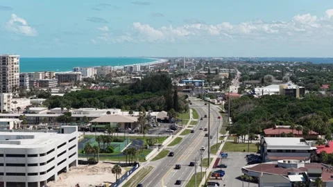 Parking garage construction rises beside tennis courts plus palm-lined highway Stock Footage 340863754