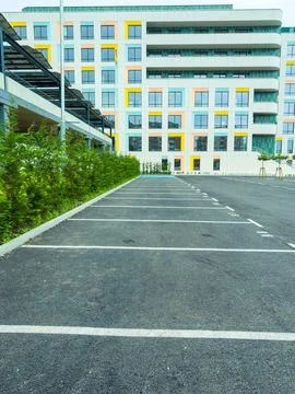 A parking lot shows empty spaces next to a modern office building. The area h Stock Photos