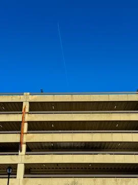 A parking structure is seen from below with multiple levels and openings. A c Stock Photos