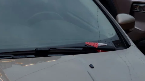 Parking ticket tucked under windshield wiper on white car with rain droplets and Stock Footage 346558850